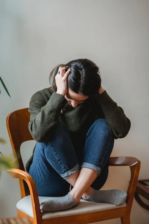A woman sitting on a sofa holding her stomach